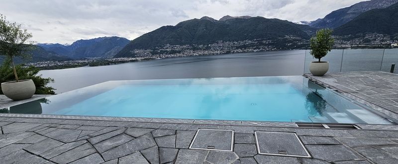 Ein Swimmingpool aus Edelstahl mit Blick auf einen See und Berge im Hintergrund. Foto von der Artmetal GmbH
