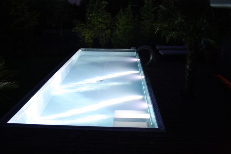 Ein grosses Schwimmbecken aus Edelstahl ist nachts beleuchtet. Foto von der Artmetal GmbH