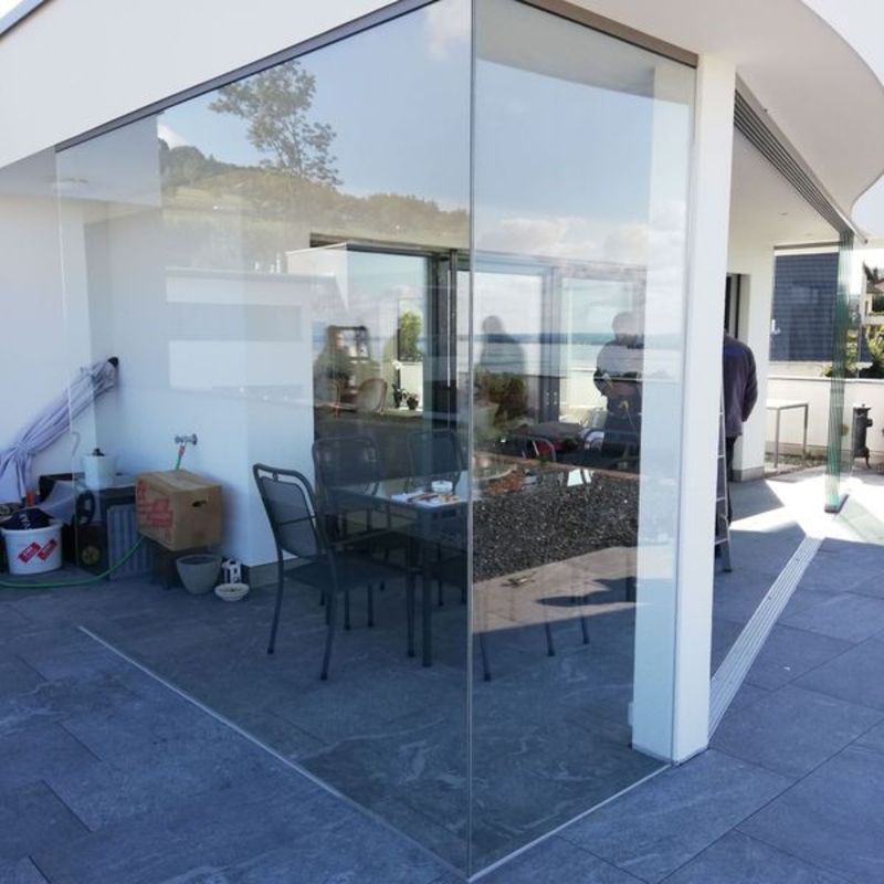 Eine Terrasse mit Glaswand und Tischen und Stühlen. Foto von der Artmetal GmbH