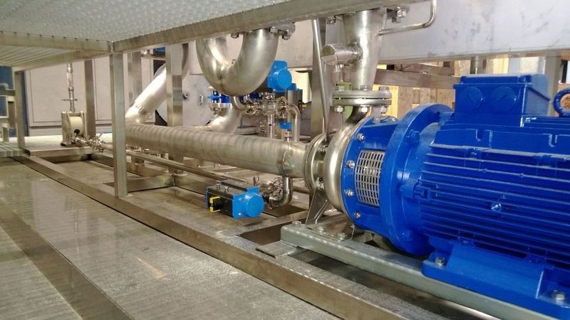 In einer Fabrik steht ein blauer Motor neben einem Rohr. Foto von der Artmetal GmbH