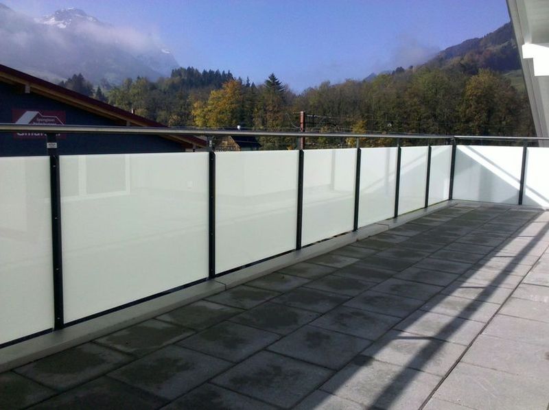 Ein Balkon mit Glasgeländer und Bergen im Hintergrund. Foto von der Artmetal GmbH