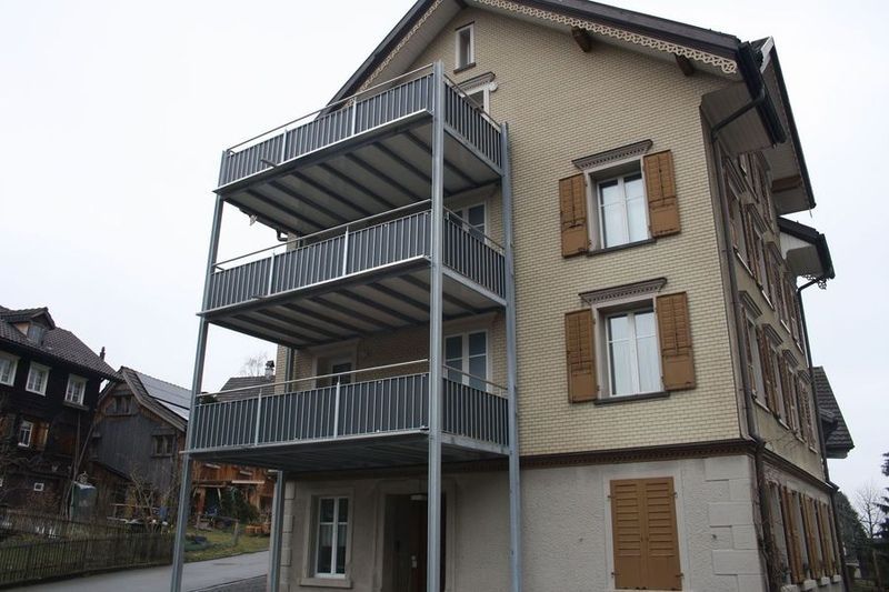 Ein grosses Gebäude mit Balkon und Fensterläden. Foto von der Artmetal GmbH