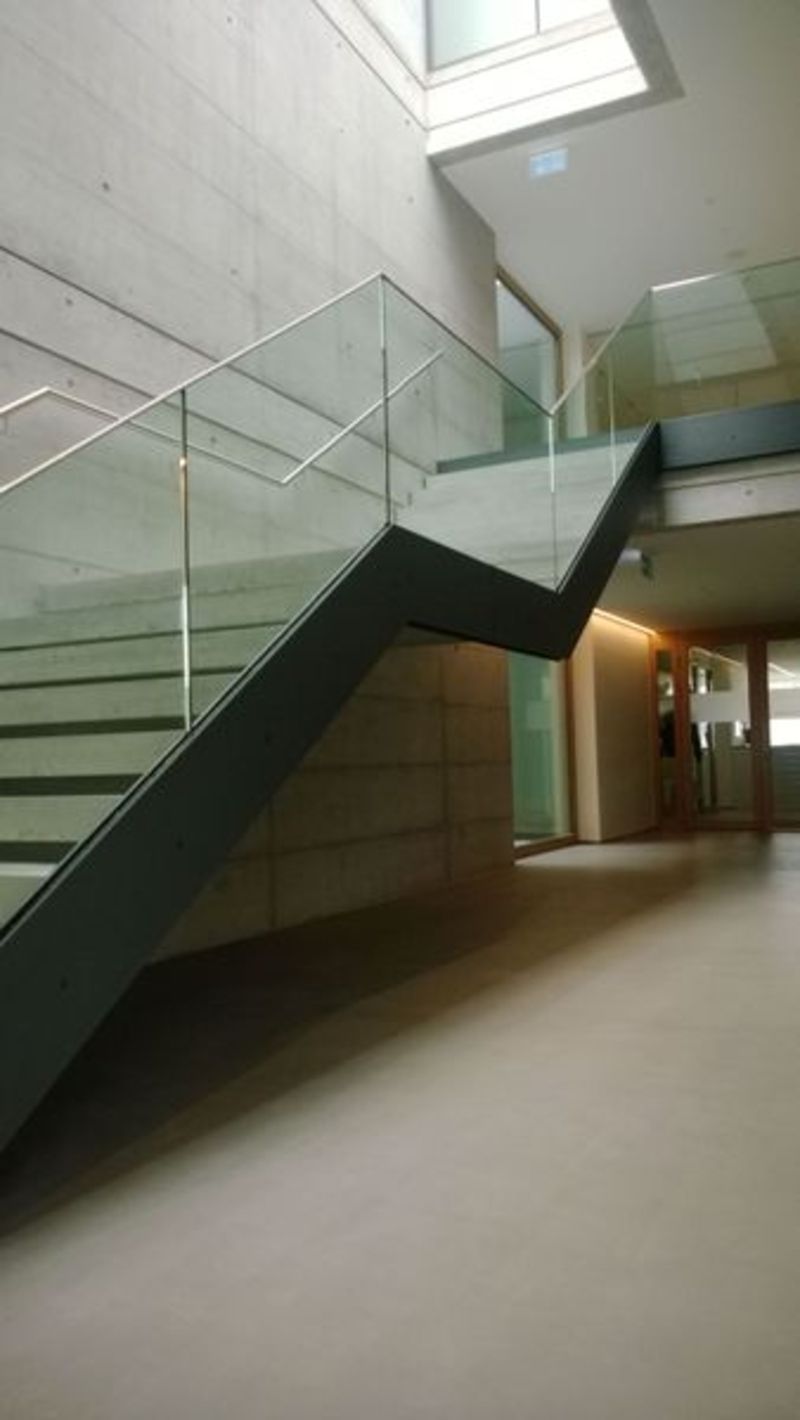 Eine Treppe mit einem Glasgeländer in einem Gebäude. Foto von der Artmetal GmbH