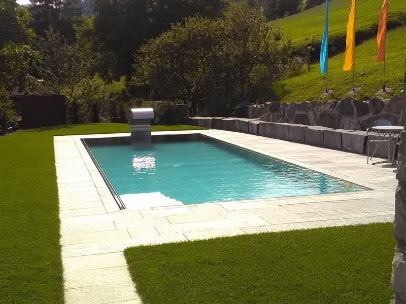 Ein grosses Schwimmbecken aus Edelstahl, umgeben von Gras und Flaggen. Foto von der Artmetal GmbH