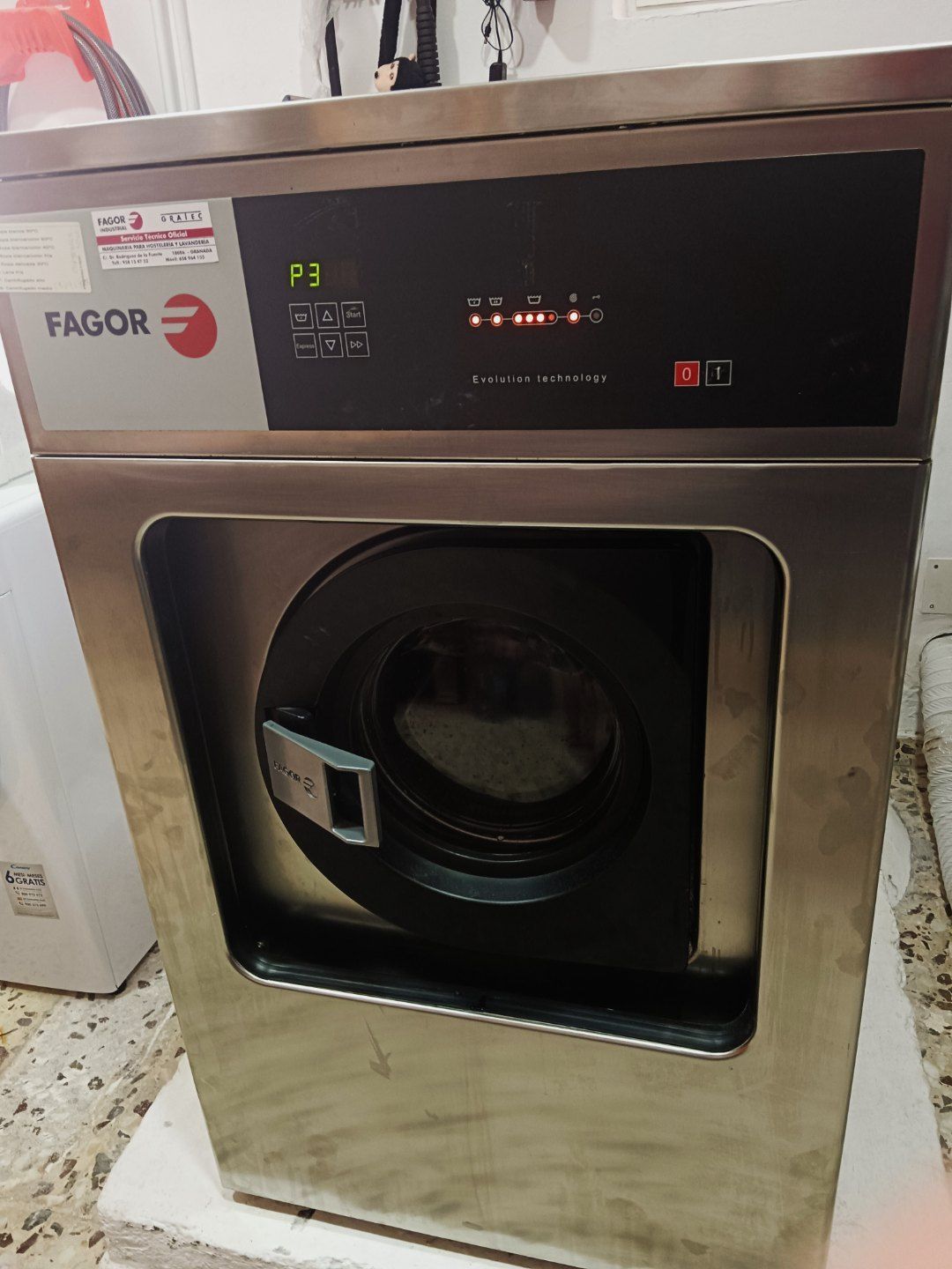 Una lavadora de acero inoxidable está sobre una mesa blanca.