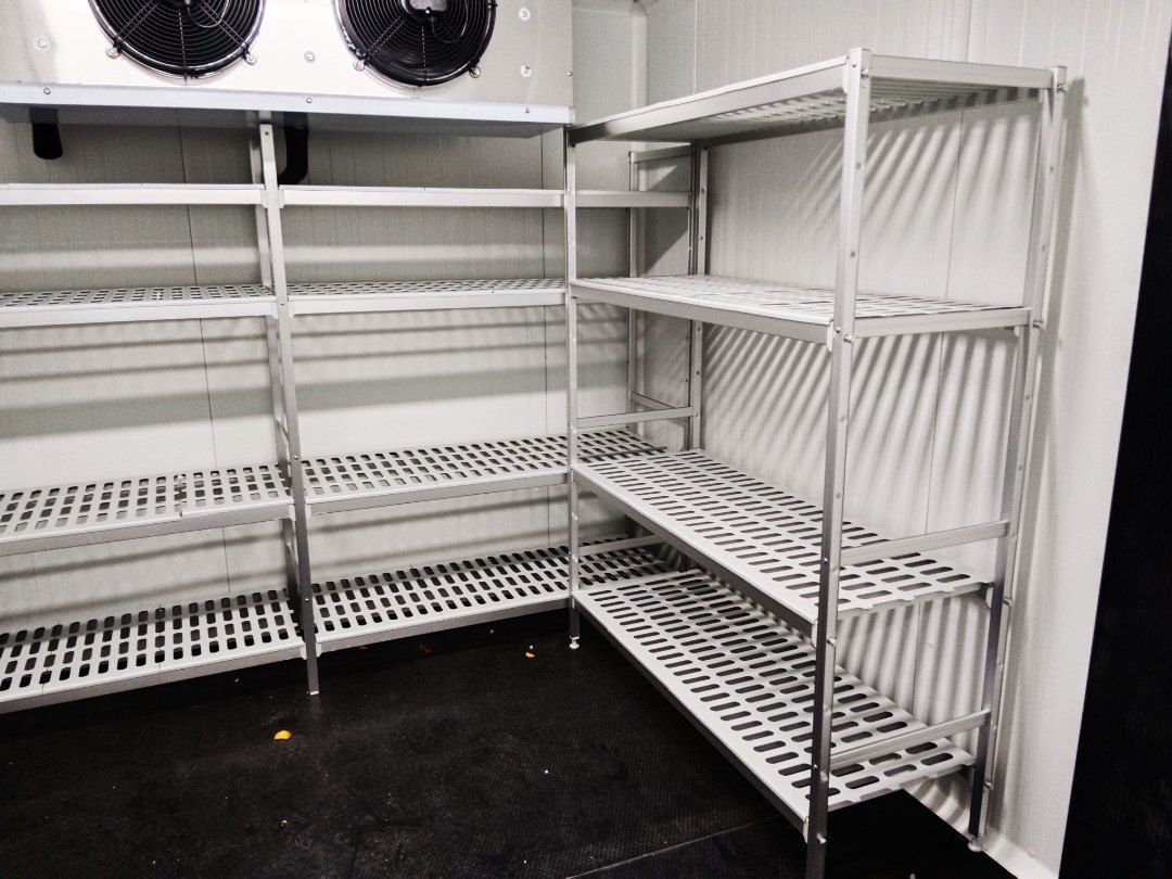 Una habitación con muchos estantes y un ventilador en la pared.