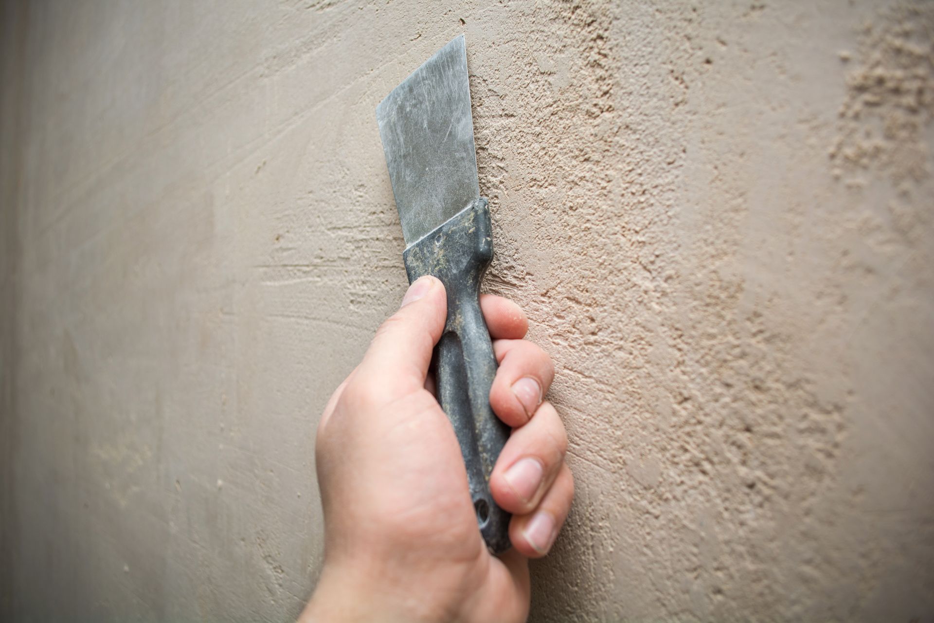Couteau à enduire noir sur un mur beige