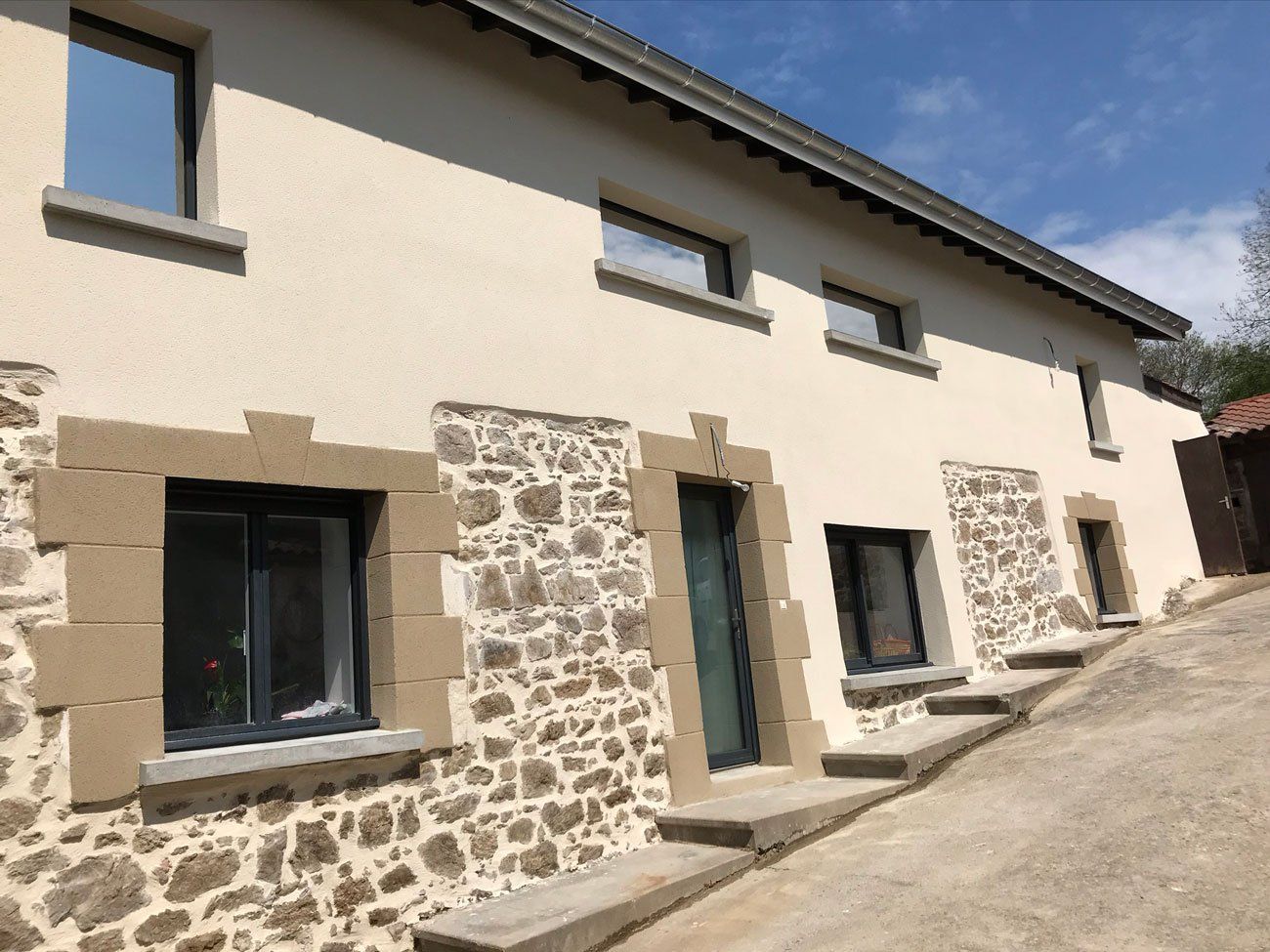 Maison en pierre avec enduit clair et avec sol en pente