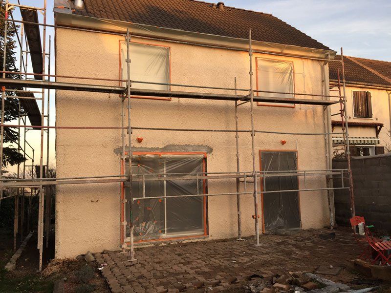 Maison avec un échafaudage et les fenêtres couvertes de protections plastiques