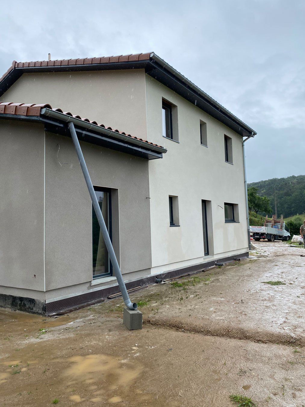 Maison blanche avec annexe grise et gouttière