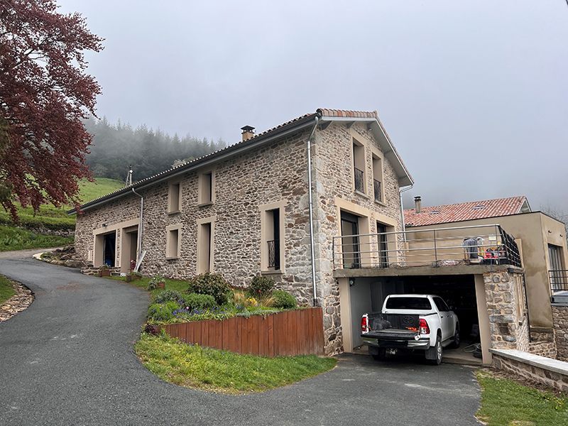 Façade d'une grande maison en pierre à flanc de colline