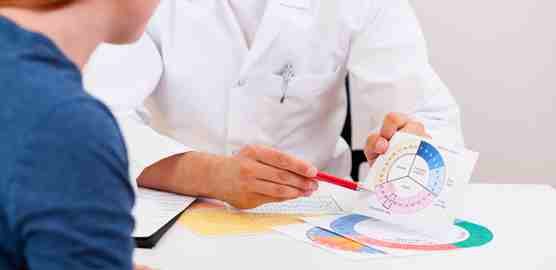 Un médico está sentado en una mesa hablando con un paciente.