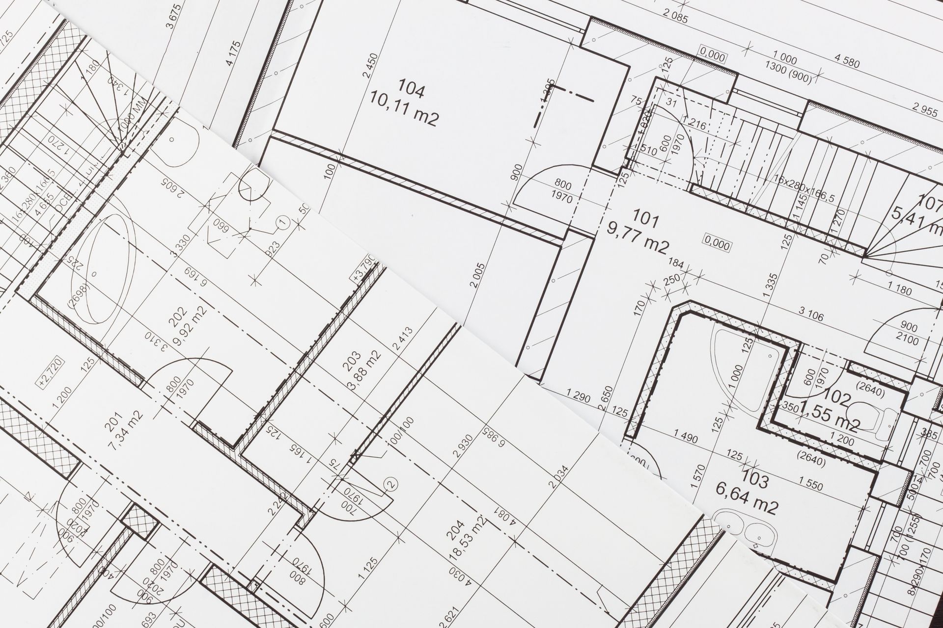 Des plans architecturaux se chevauchent ; les lignes, les dispositions des pièces, les dimensions et les notations sont visibles.
