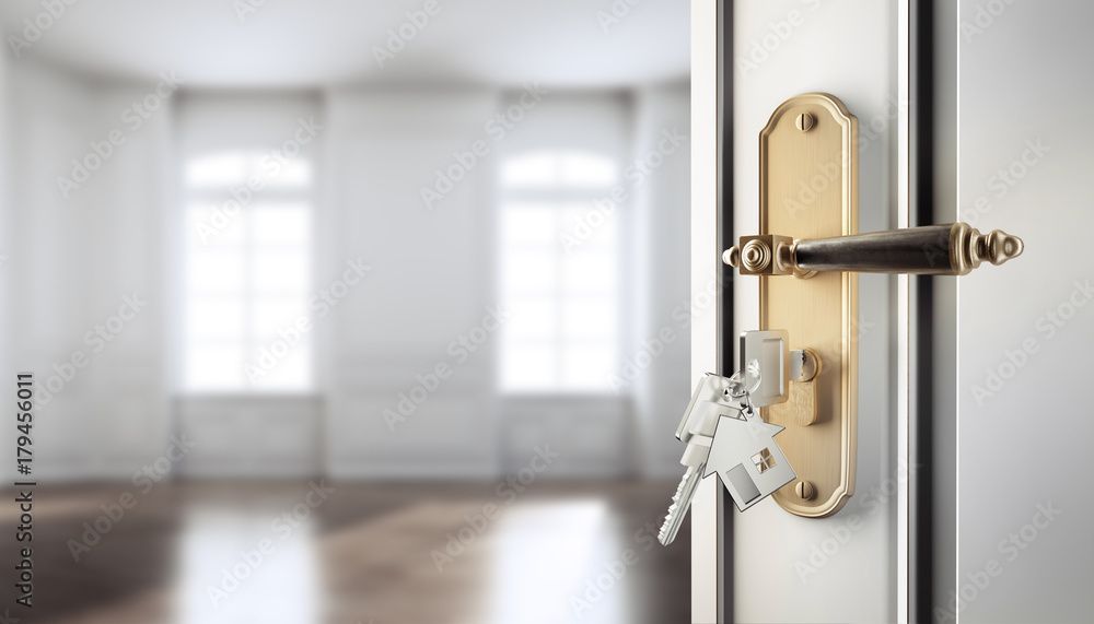 Porte ouverte avec clés, menant à une pièce vide et lumineuse avec des fenêtres.