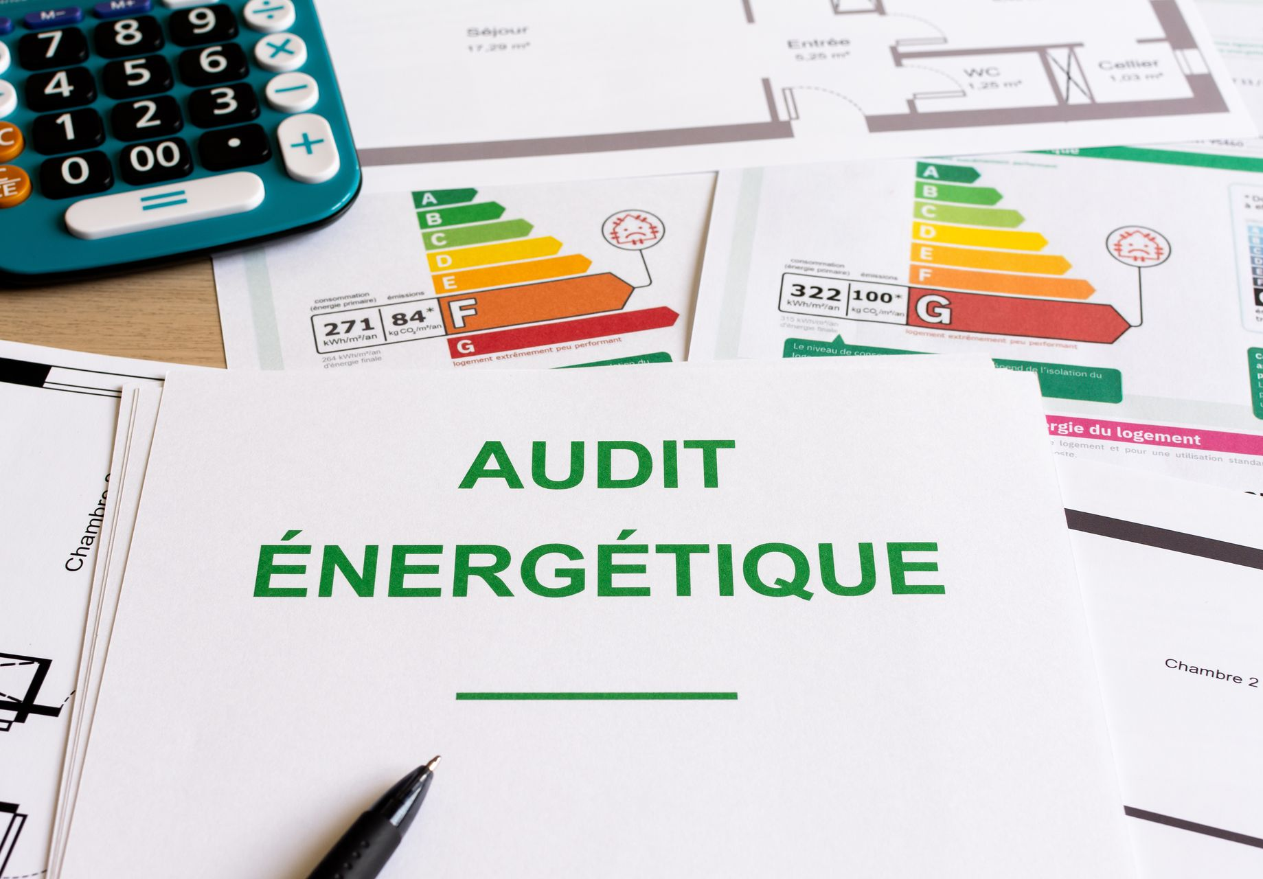 Livre blanc avec « AUDIT ÉNERGÉTIQUE », calculatrice et étiquettes d'efficacité énergétique sur un bureau.