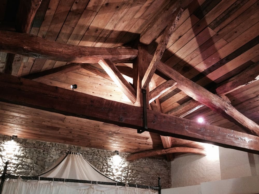 un lit avec un plafond en bois et un rideau blanc