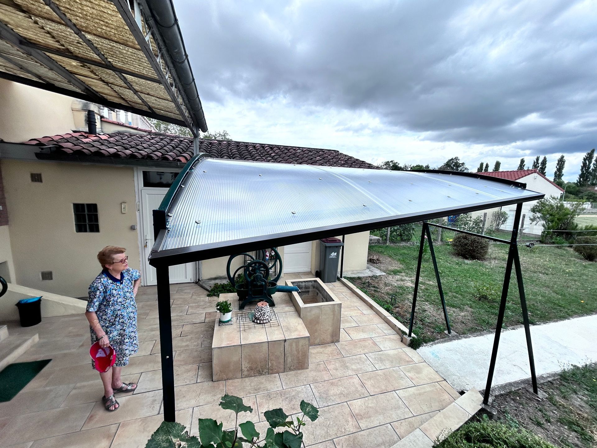 un petit garçon debout sur une terrasse avec un grill