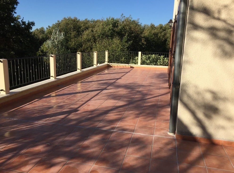 une terrasse avec un sol carrelé et une clôture