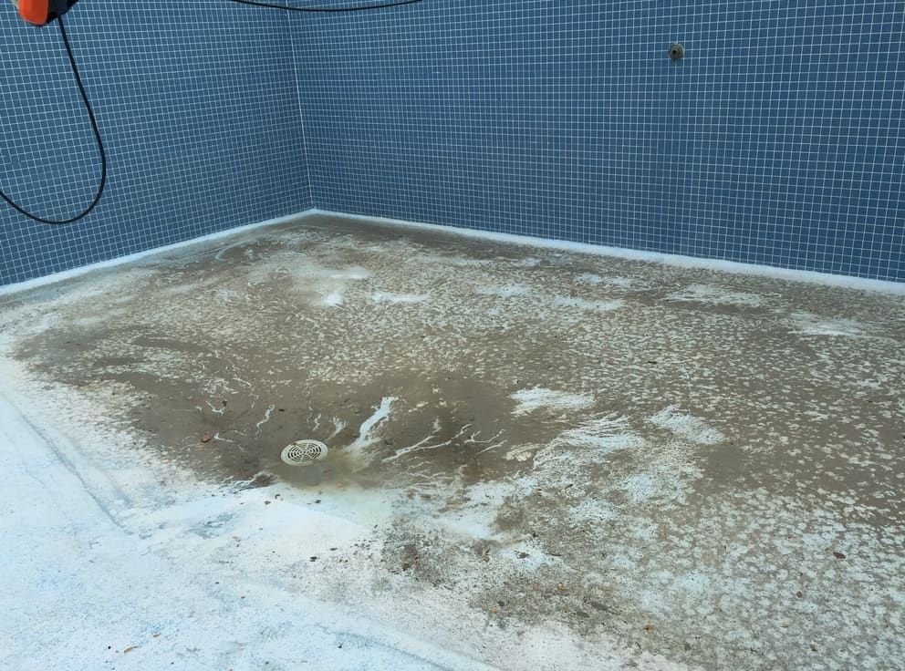 un sol de salle de bain sale avec un mur carrelé bleu