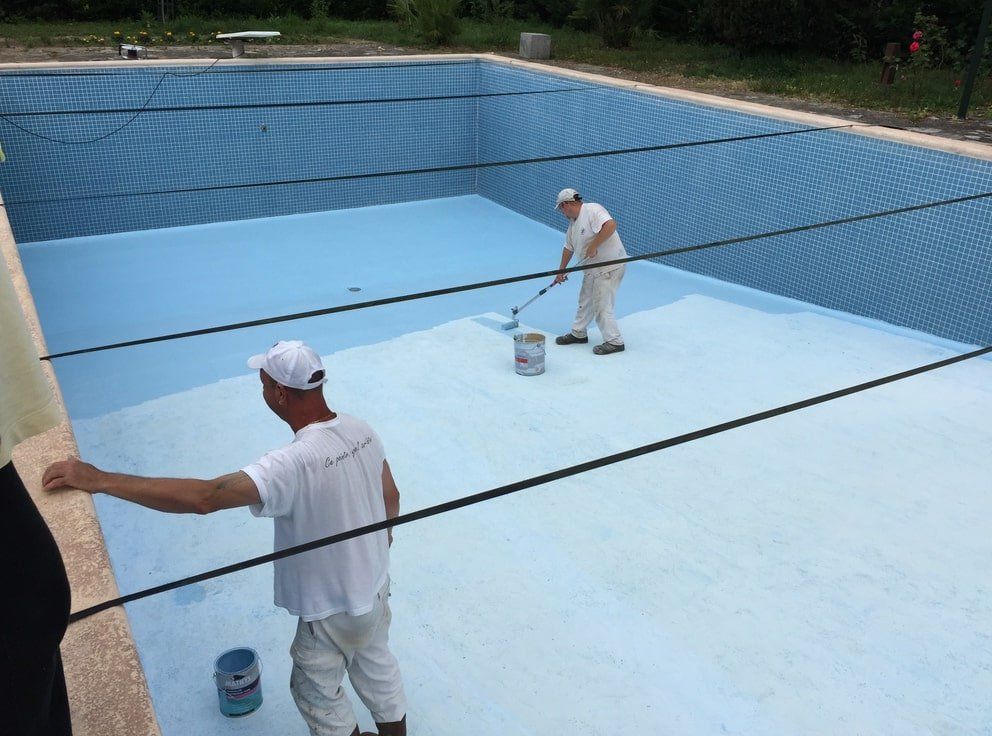 deux hommes peignant une piscine avec de la peinture bleue