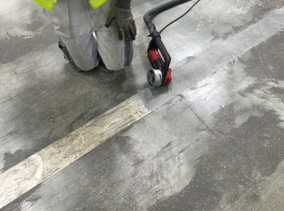 un homme utilisant un outil électrique pour nettoyer un sol en béton