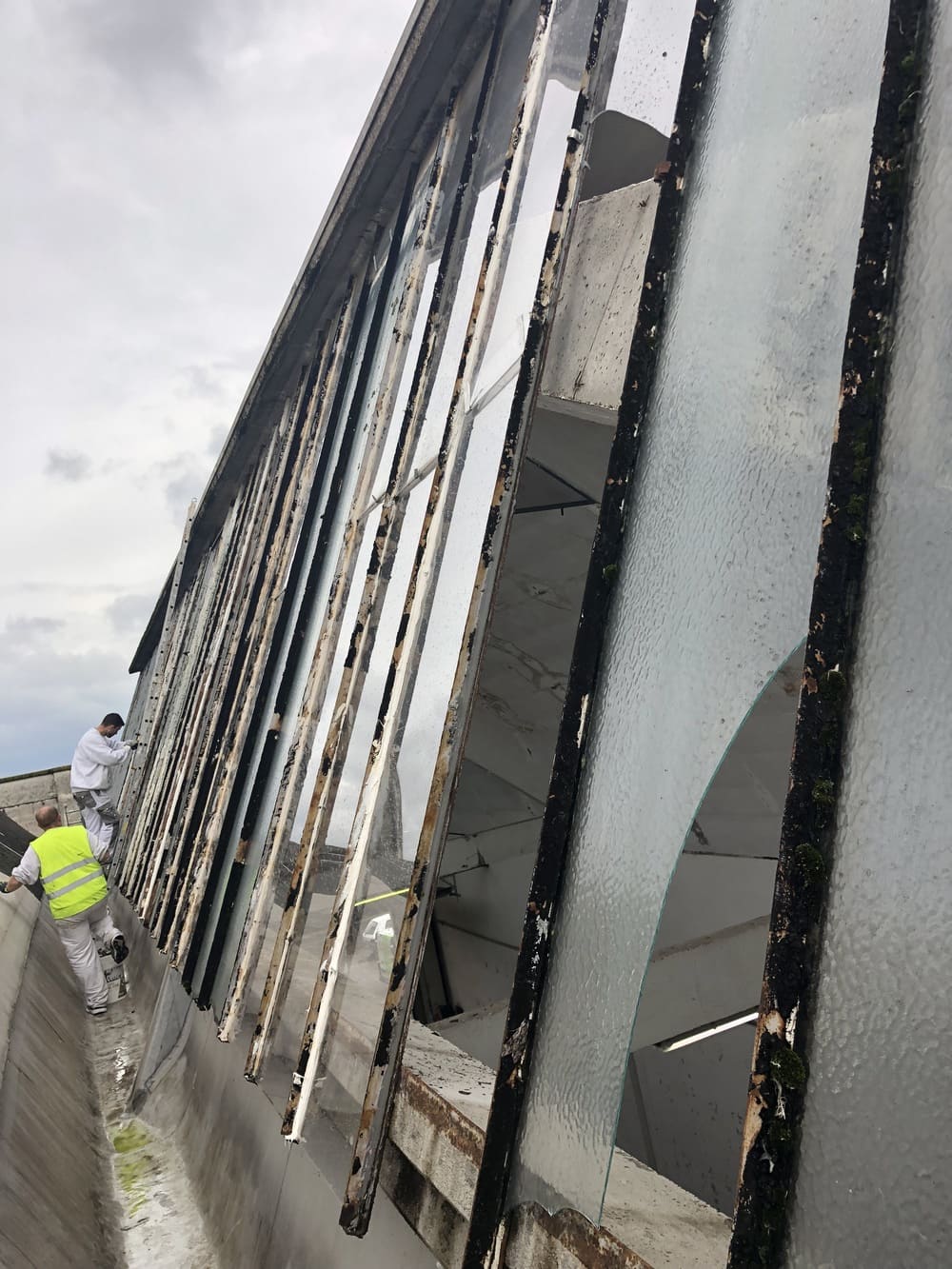 un homme debout à côté d’un bâtiment avec une fenêtre cassée