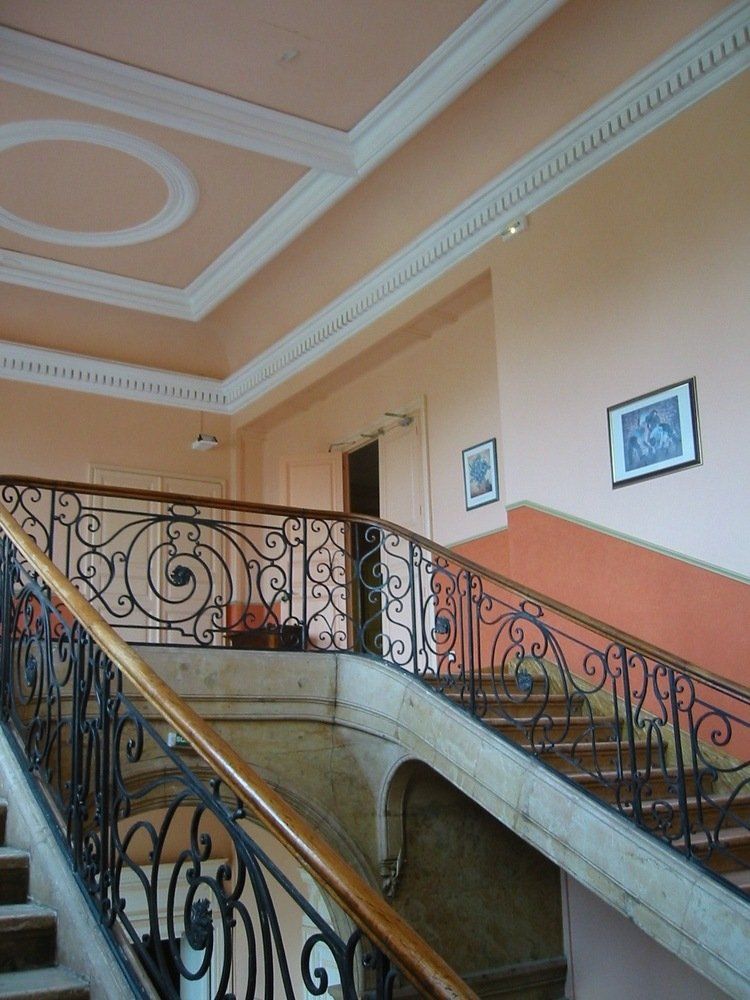 Un escalier avec une rampe en métal et une peinture au mur.