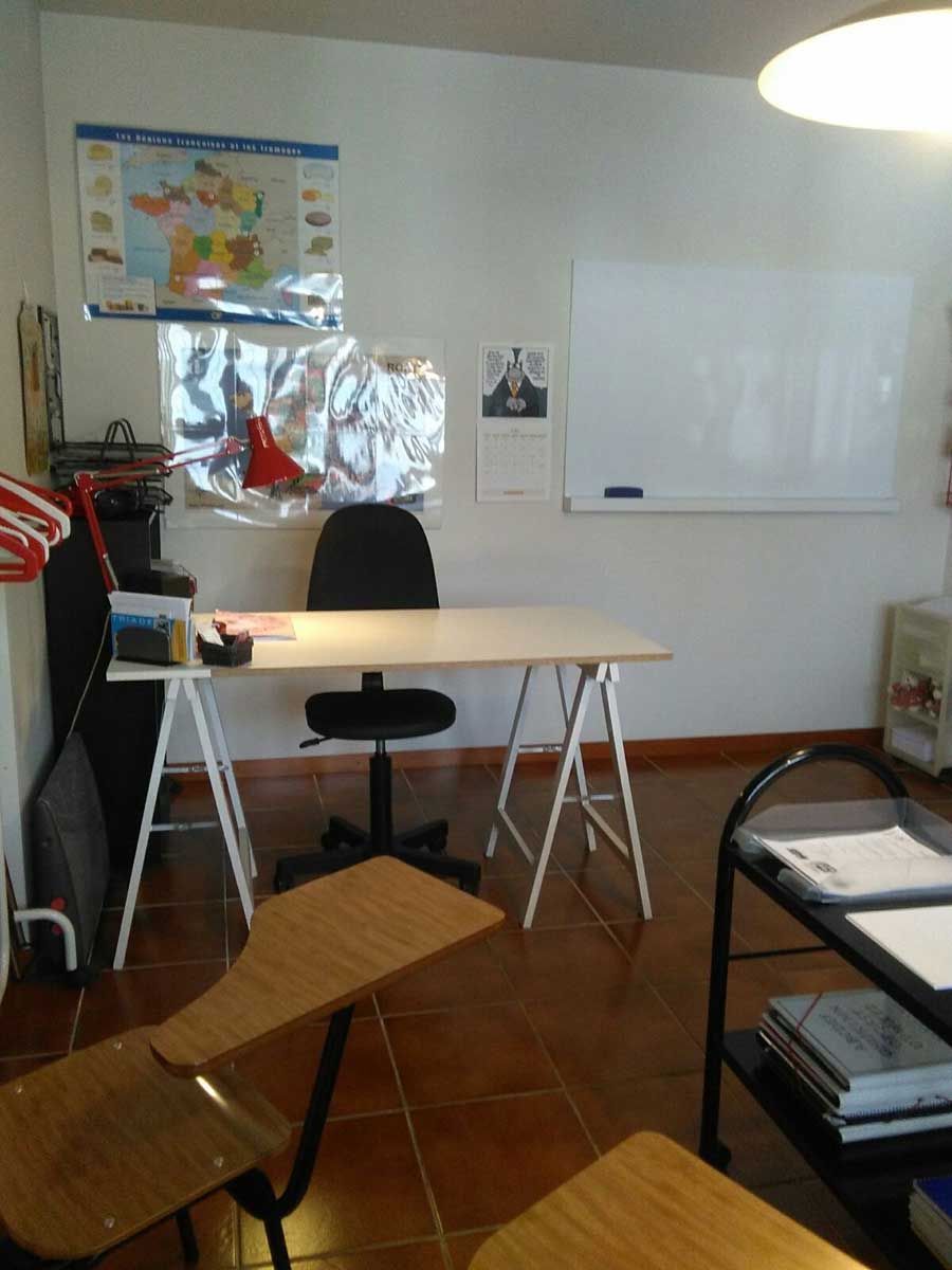 Un aula con un escritorio y sillas y una pizarra.