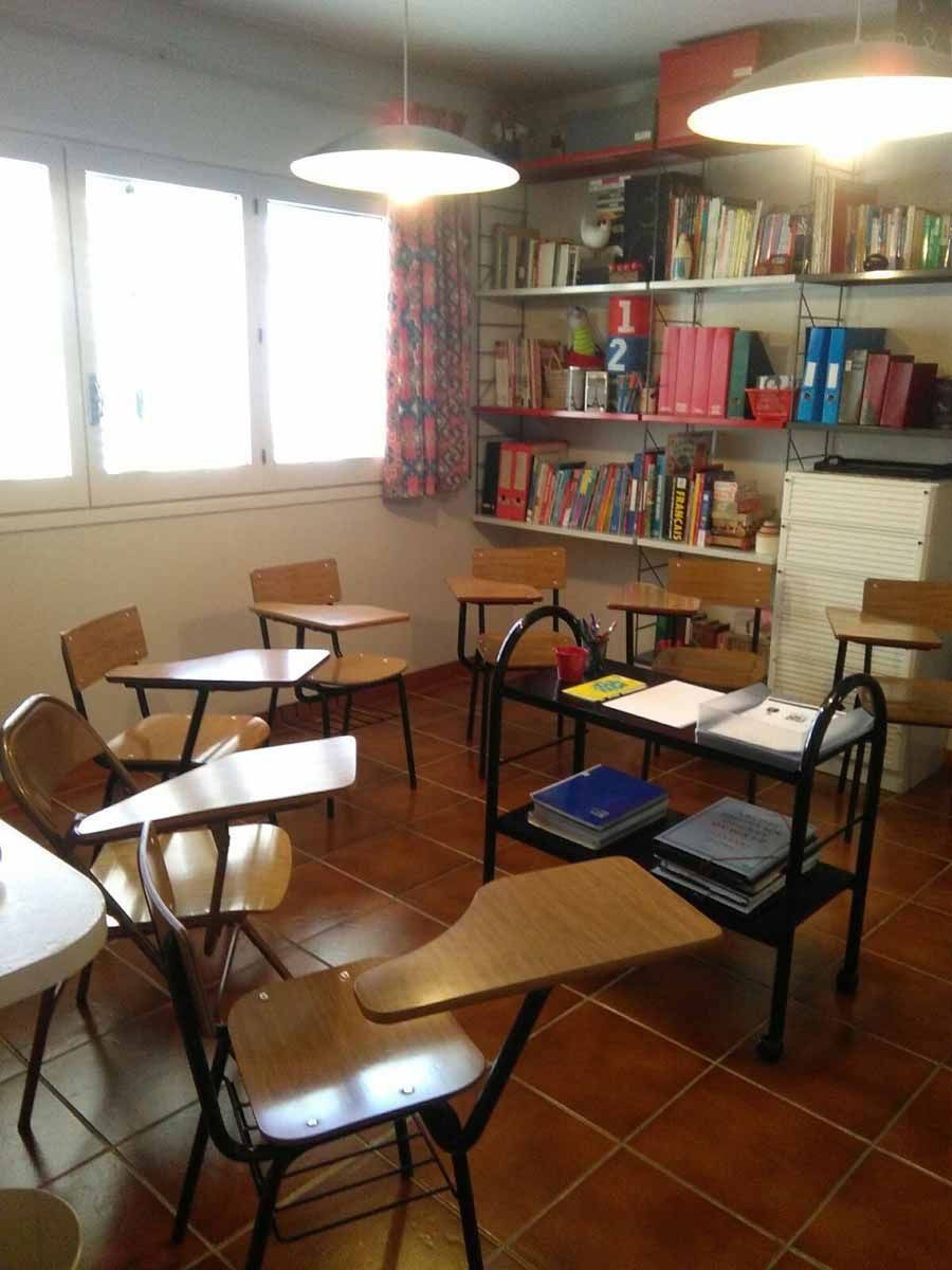 Un aula con mesas y sillas y libros en los estantes.