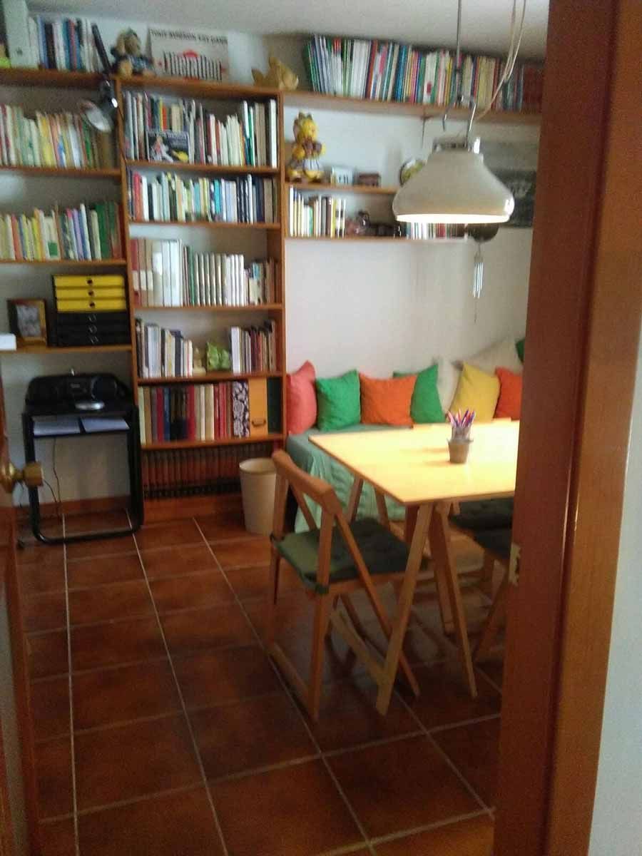 Una sala de estar con una mesa y sillas y muchos libros en los estantes.