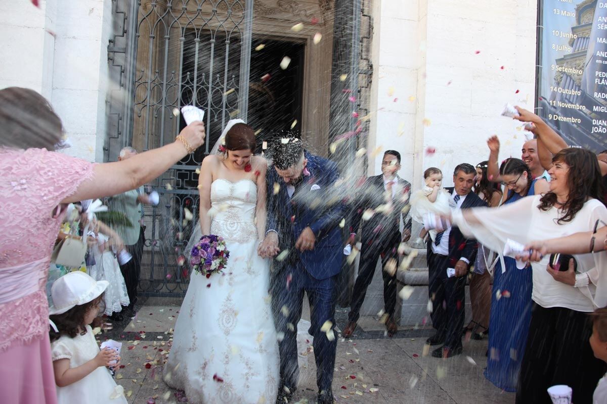 Os recém-casados foram banhados por confetes ao saírem de um prédio com os convidados;