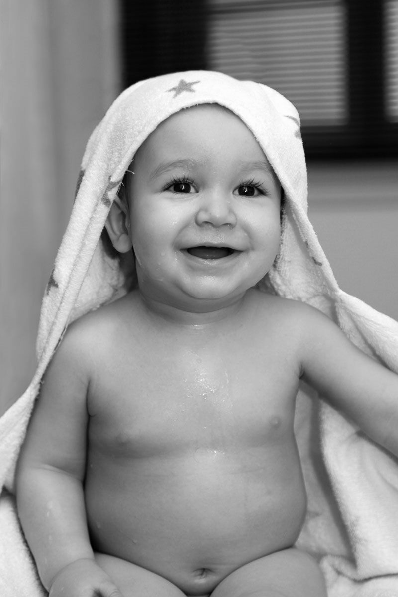 Bebê sorridente enrolado em uma toalha com estampa de estrelas, possivelmente após o banho.