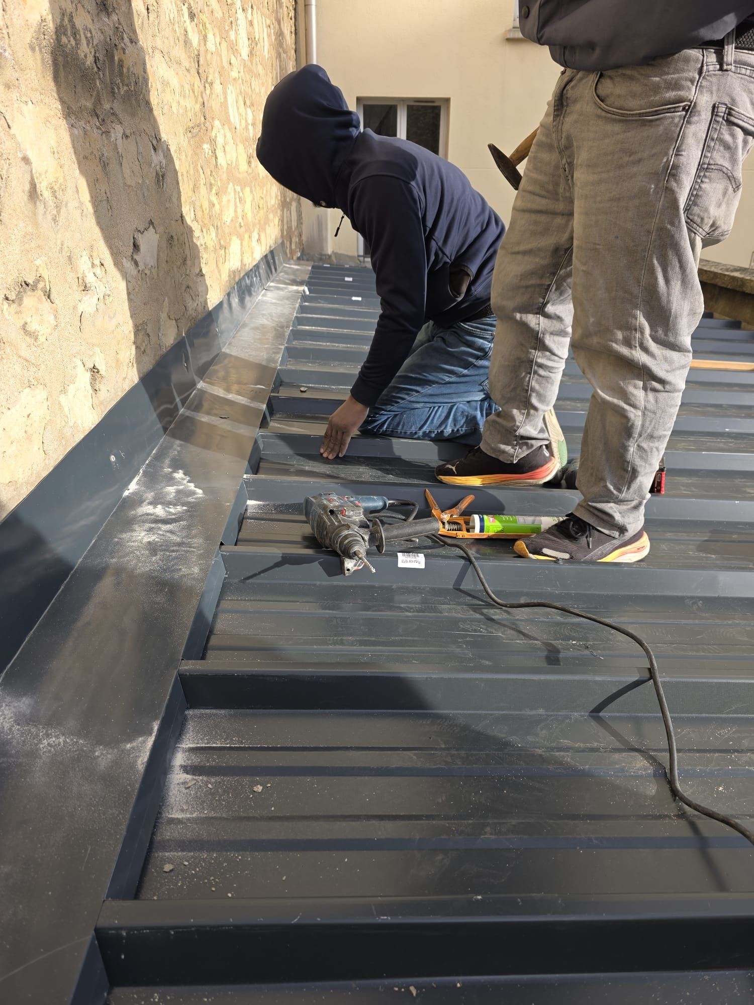 Coin d'un bâtiment en briques avec fenêtres, garnitures et détails décoratifs, sous un ciel bleu.