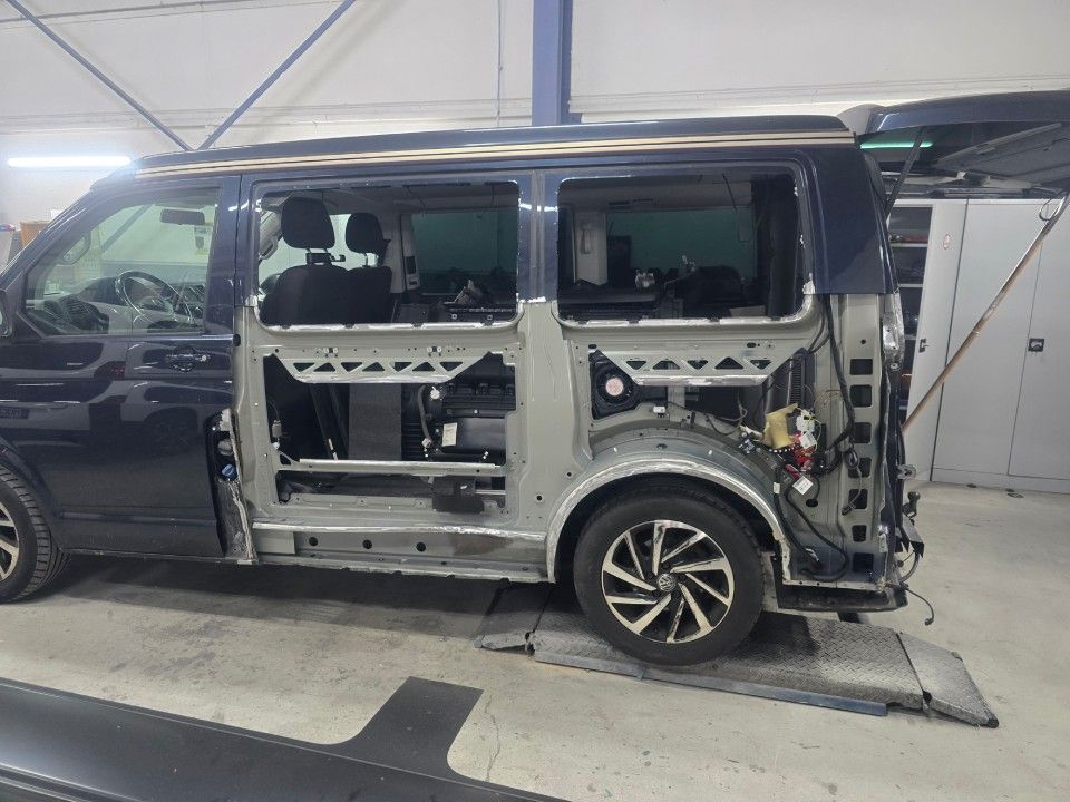 Blauer Lieferwagen, bei dem eine Seitenwand entfernt wurde, wodurch der innere Rahmen und die Räder sichtbar werden.