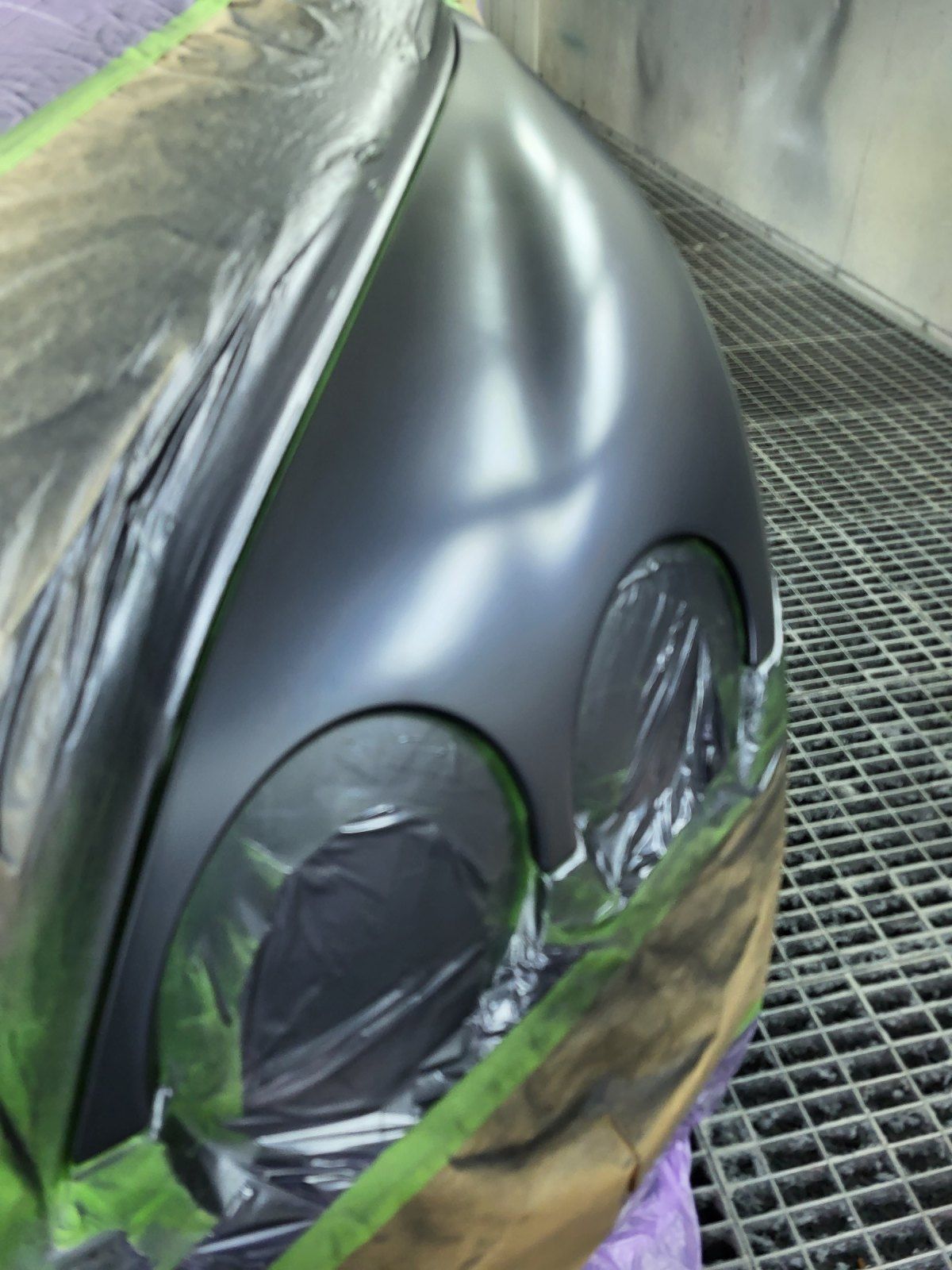 Der vordere Kotflügel des Wagens wurde frisch mattschwarz lackiert. Die Scheinwerfer sind mit Plastikfolie abgedeckt und mit grünem Klebeband abgeklebt.