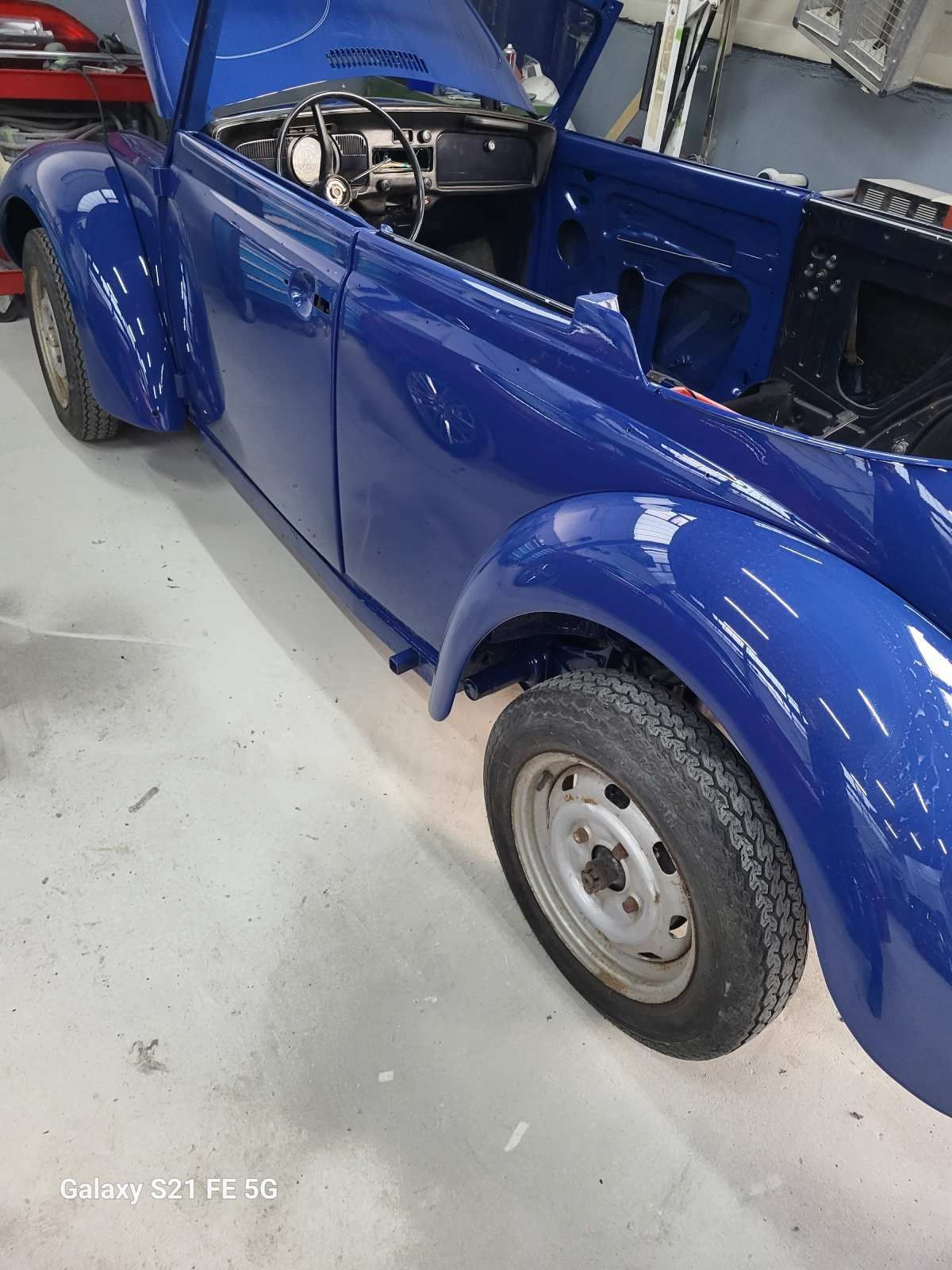 Blaues, klassisches Cabriolet mit geöffnetem Verdeck in einer Garage.