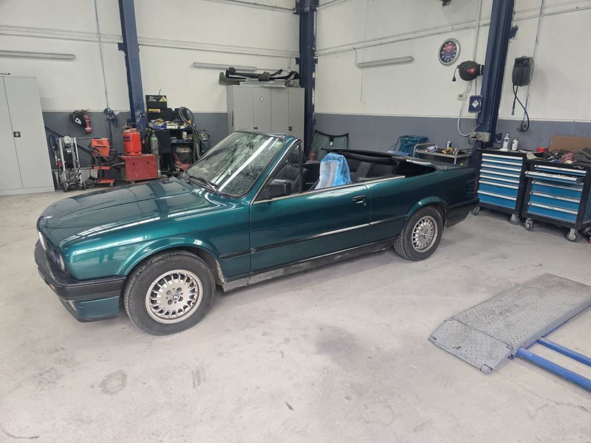 Grünes Cabriolet in einer Garage mit Werkzeugen und Ausrüstung.