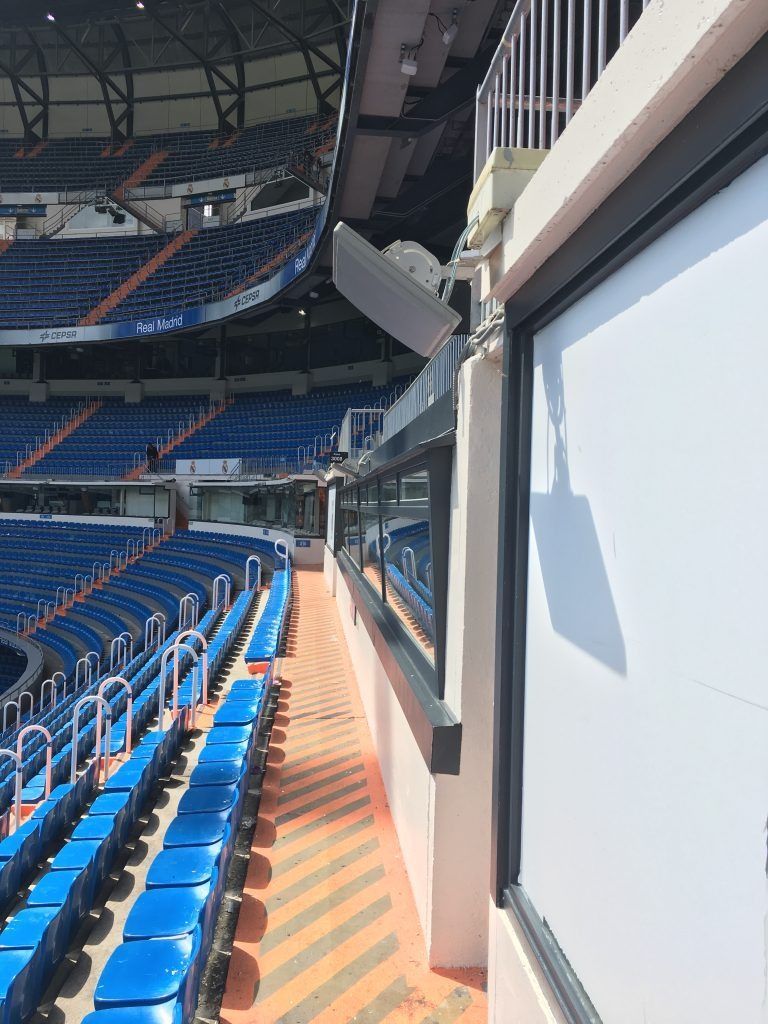 Un estadio con filas de asientos azules y una ventana.