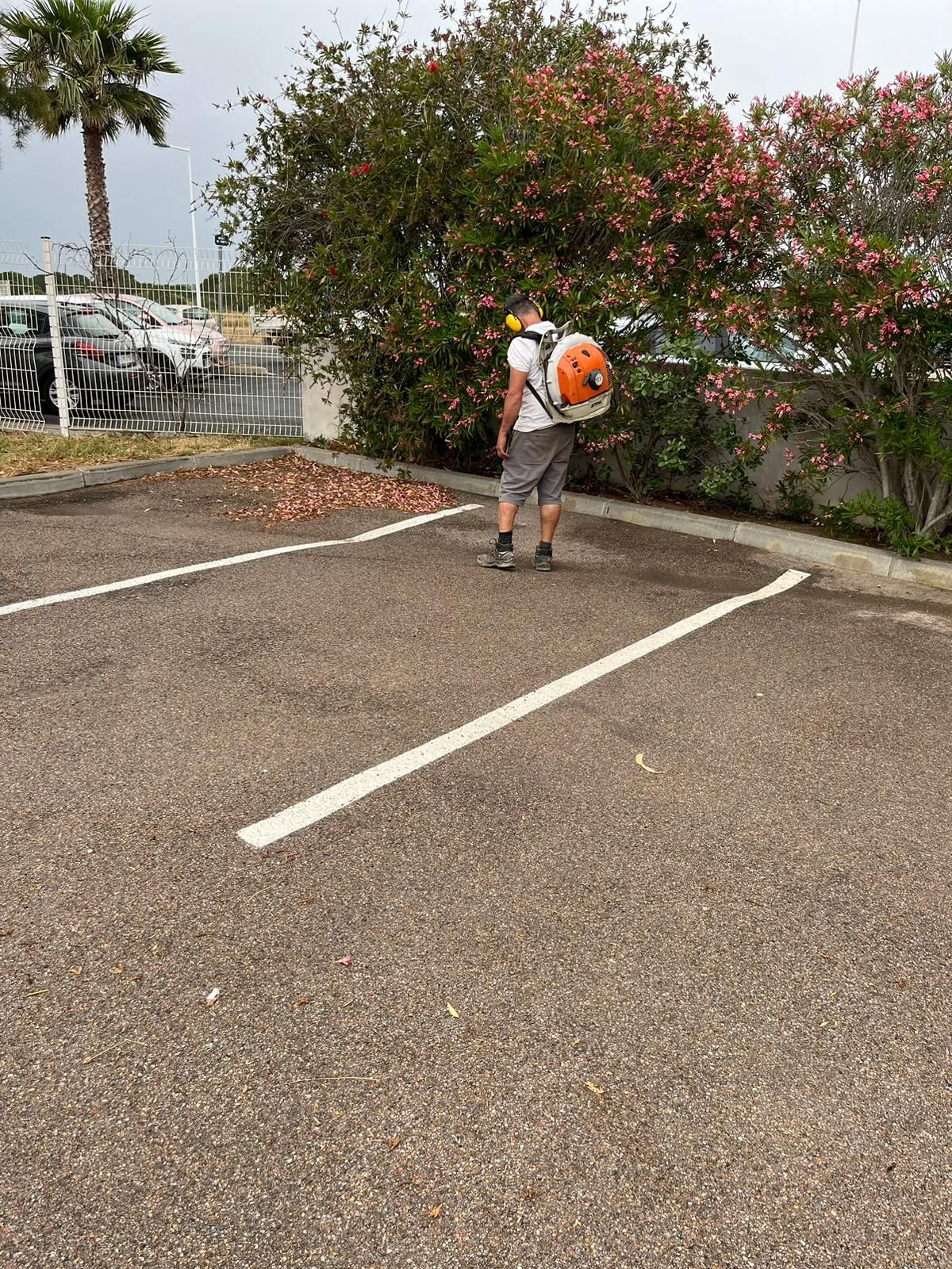 Employé de Paysage Sans Limite avec un souffleur de feuilles sur un parking