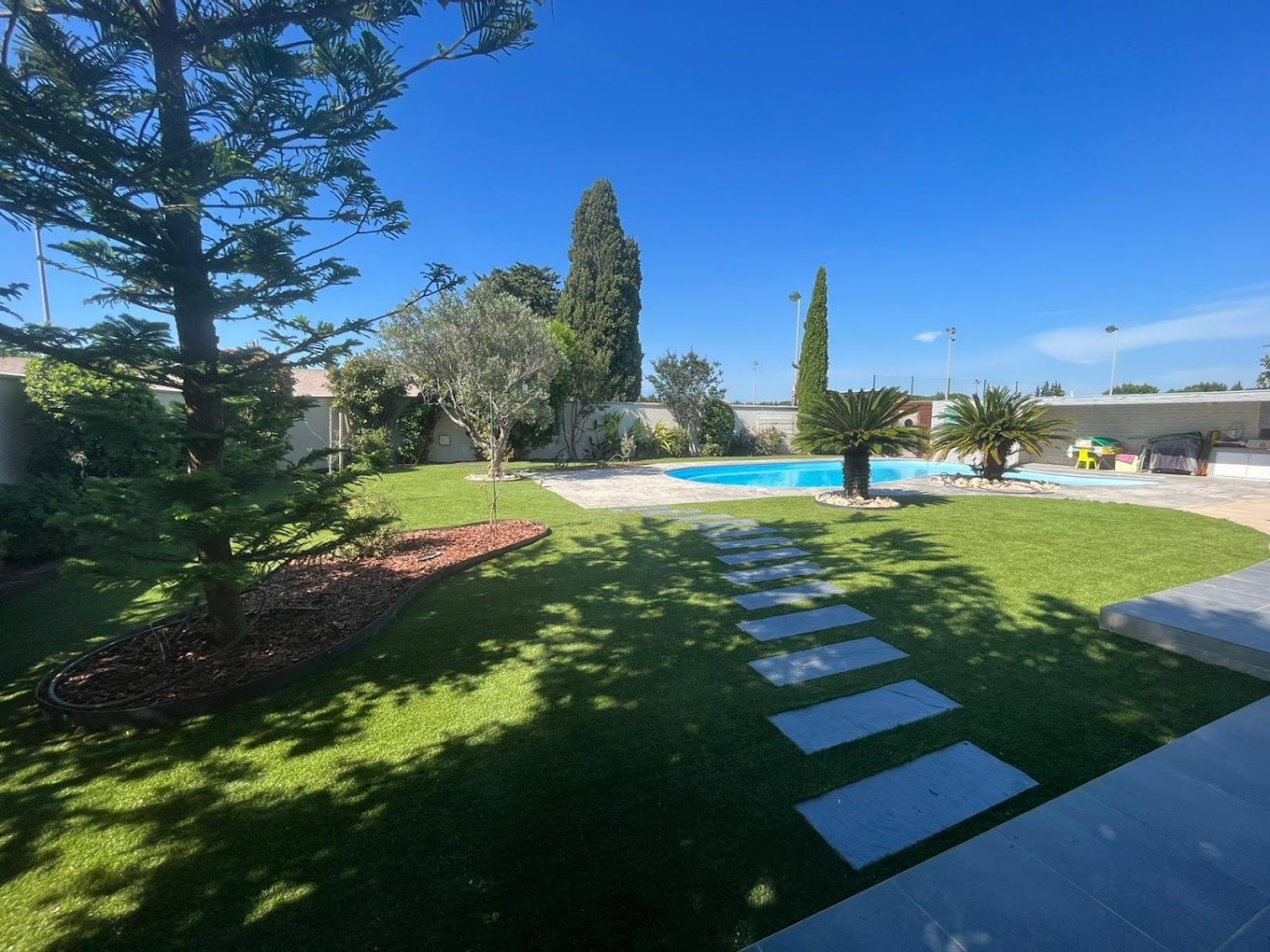 Grand jardin entretenu avec une piscine et des pas japonais