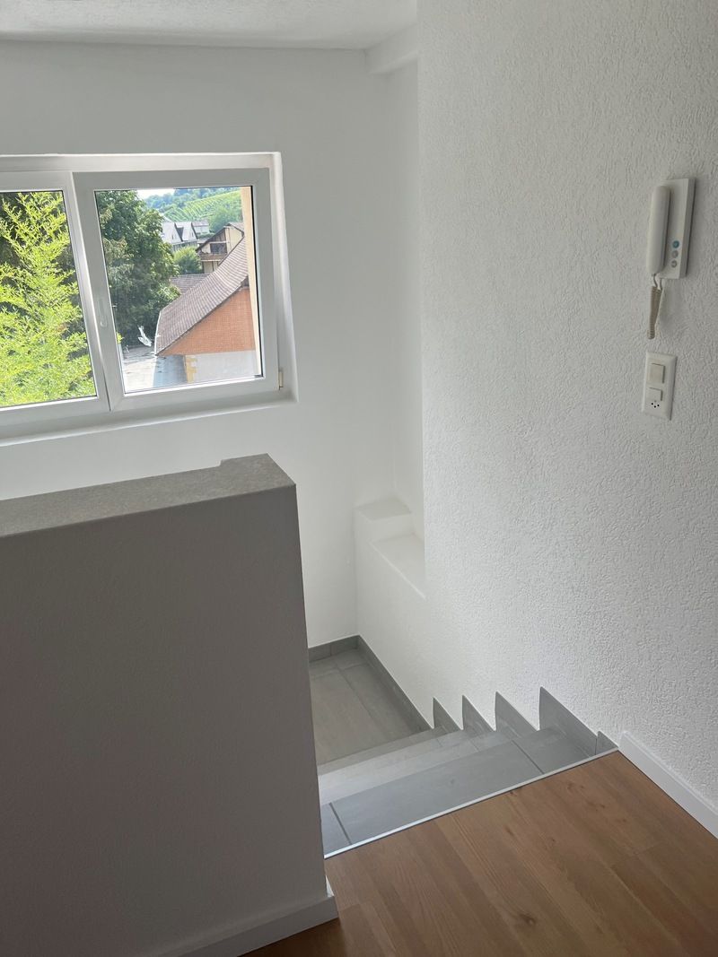 Un escalier avec une fenêtre et un téléphone sur le mur.