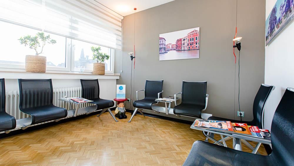 Ein Wartezimmer mit vielen Stühlen und einem Tisch.