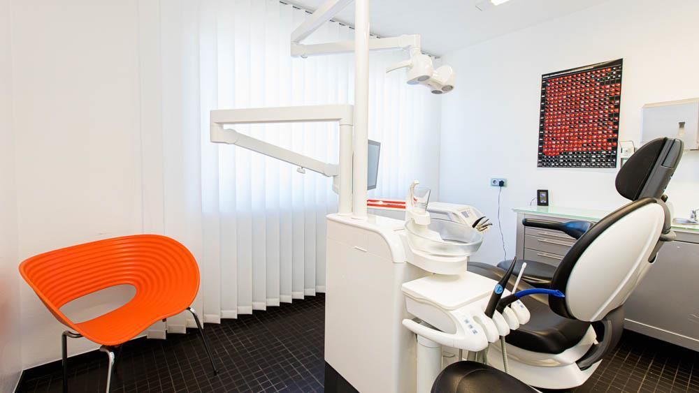 Eine Zahnarztpraxis mit einem orangefarbenen Stuhl und einem Zahnarztstuhl