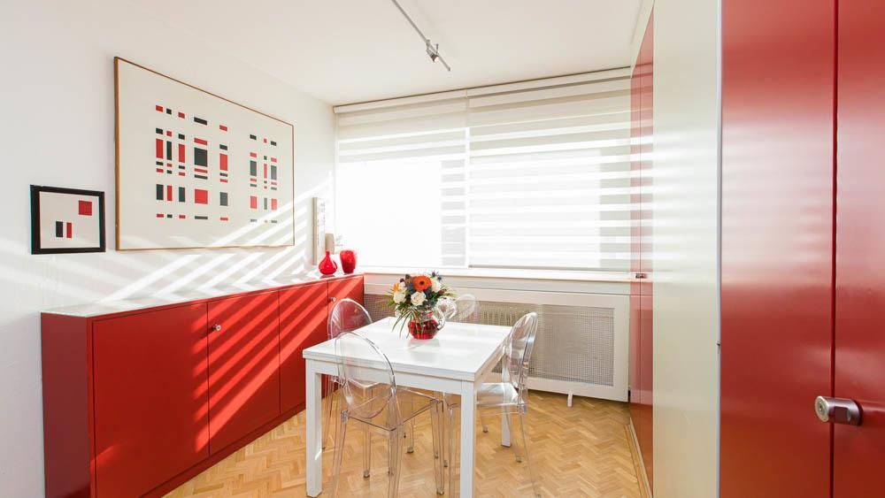 Ein Esszimmer mit einem Tisch und Stühlen und einer Vase mit Blumen auf dem Tisch.