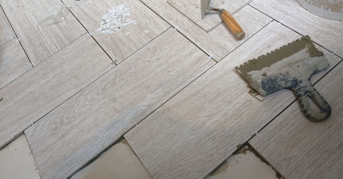 Una paleta está colocada sobre un suelo de baldosas al lado de un martillo.