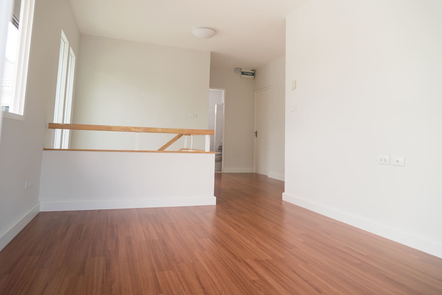 Una habitación vacía con pisos de madera y paredes blancas.