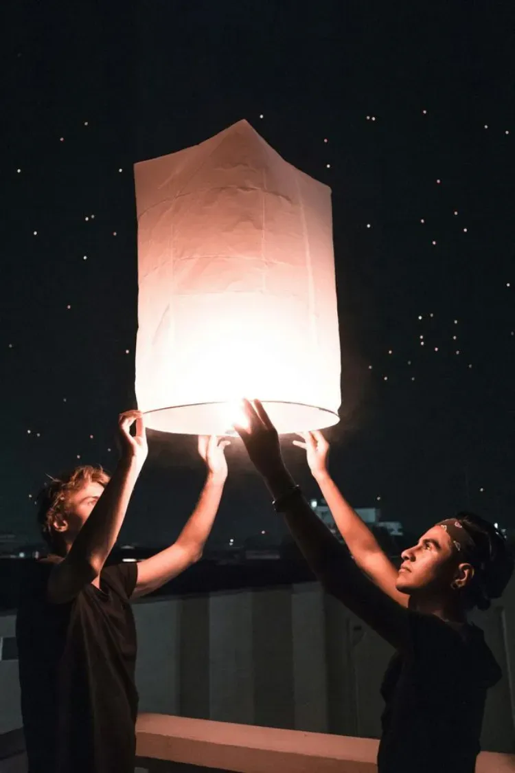 Una persona duerme en una cama rodeada de nubes brillantes y esponjosas contra un cielo azul, sosteniendo una de las nubes iluminadas.