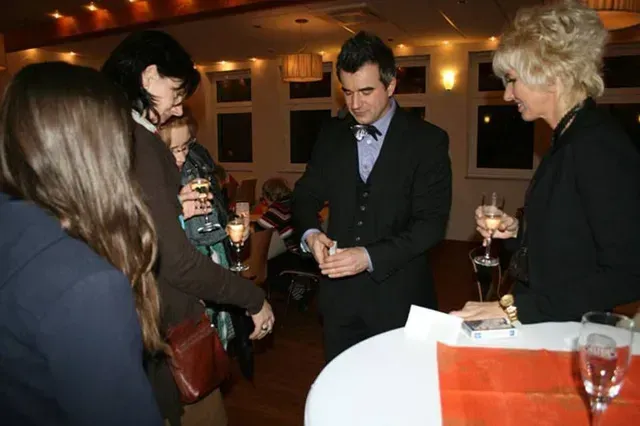 Gäste unterhalten sich bei einem Sekt-Empfang, während ihnen von Pascal Thomas Zaubertricks präsentiert werden