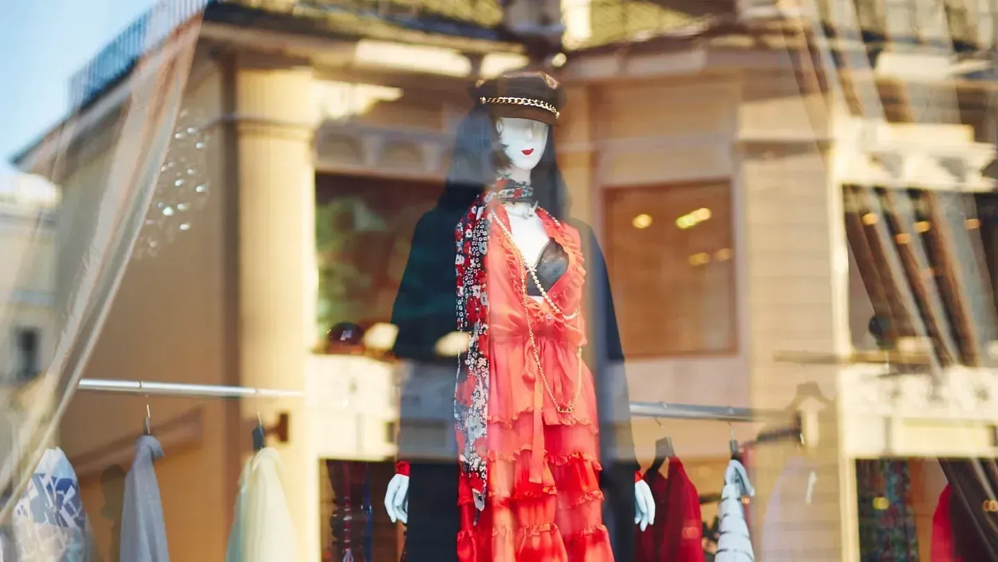 Un maniquí con un vestido rojo está de pie en el escaparate de una tienda.