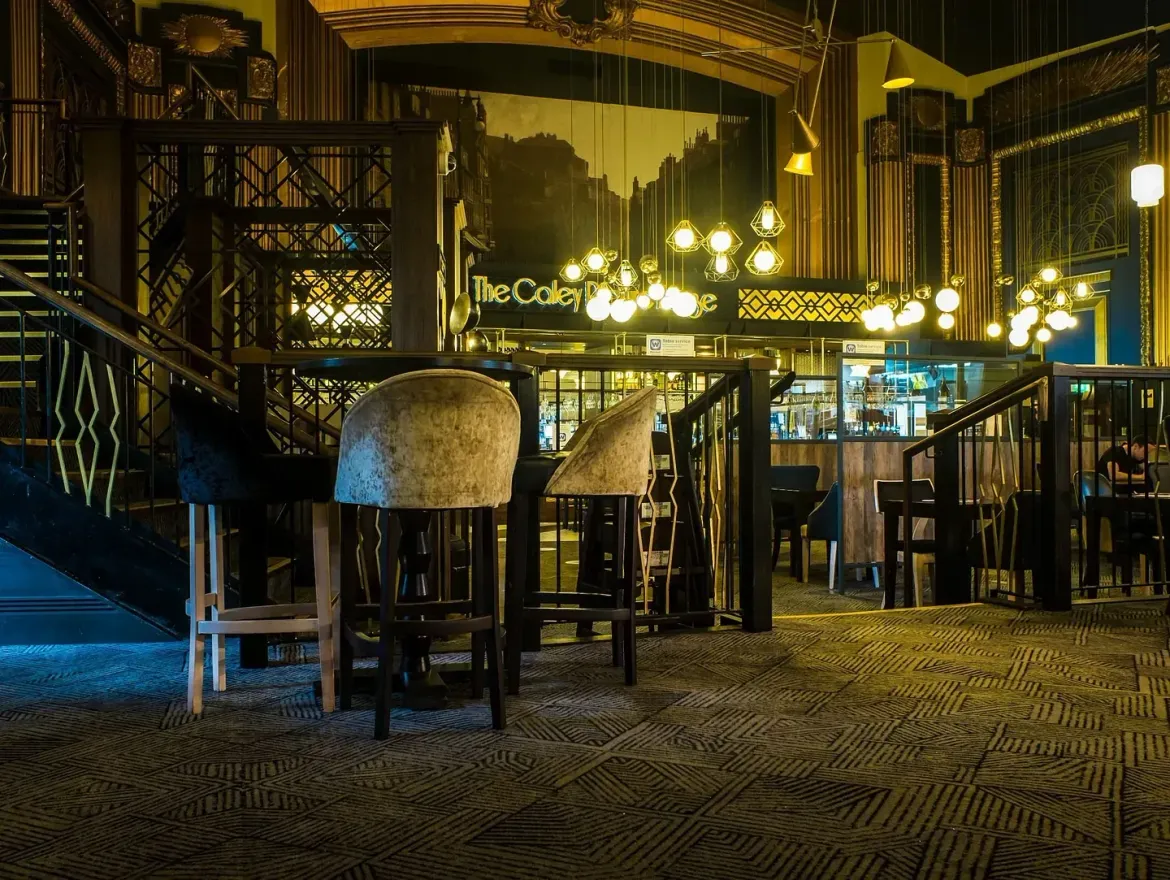 Un restaurante con mesas y sillas y escaleras al fondo.